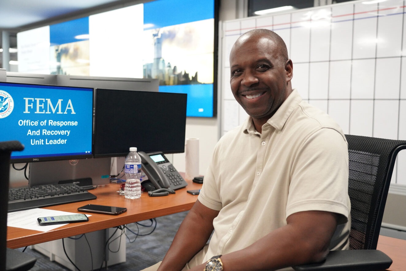 Smiling man in front of a computer.