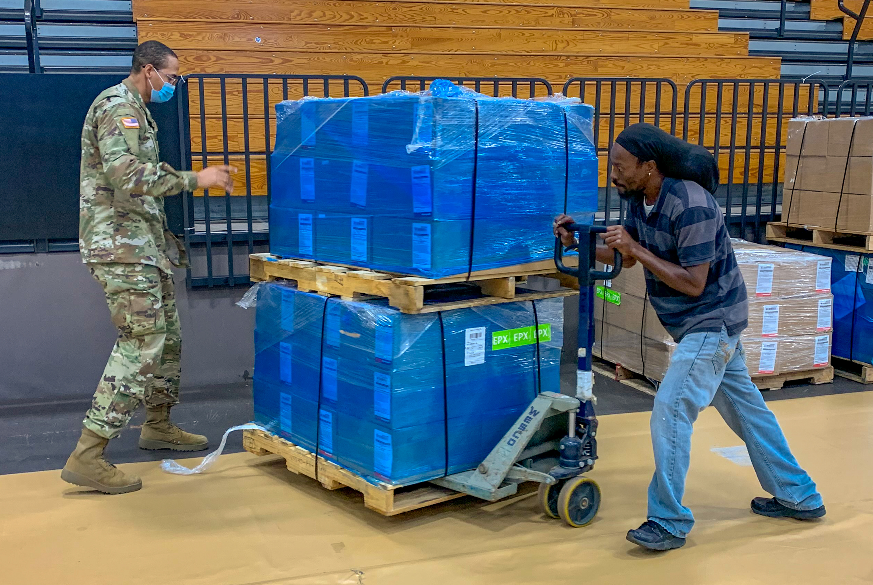 Logistics' staffer Keshawn Christopher, right, gets a hand from V.I. National Guard Specialist Kurtney Davis with a pallet of personal protective equipment during the build-out of the island's Community Vaccination Center at the University of the Virgin Islands’ Sports and Fitness Center.