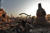 A burned tricycle sits as the sun sets over a neighborhood reduced to ash. 